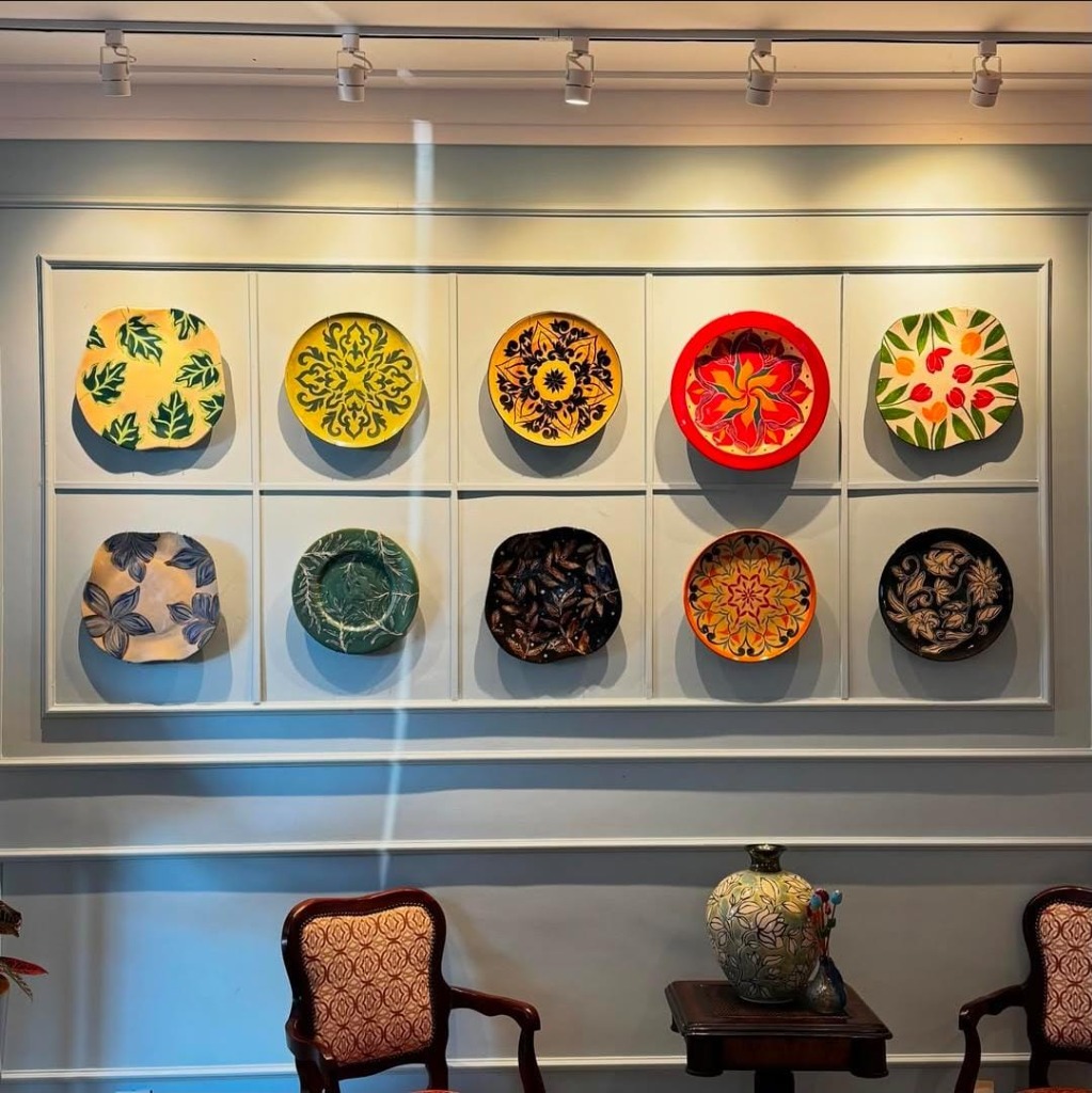 Composição de galeria com 10 pratos decorativos de cerâmica e vaso autoral expostos em ambiente elegante