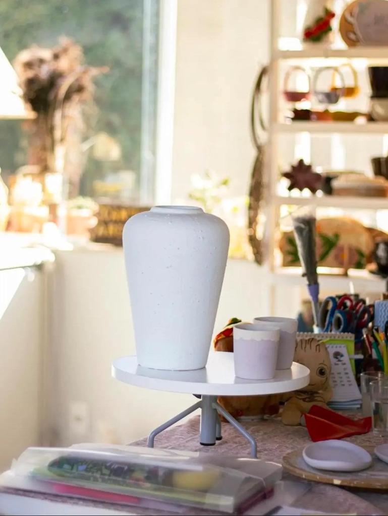 Vaso cerâmico artesanal sobre torno de ateliê com luz natural
